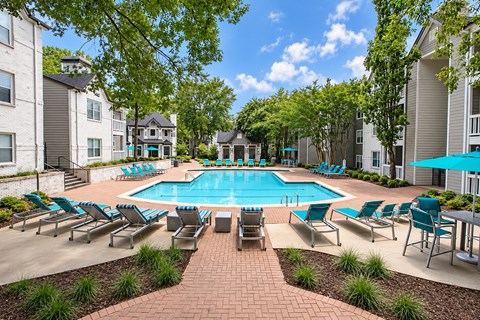 A swimming pool surrounded by lounge chairs and trees.