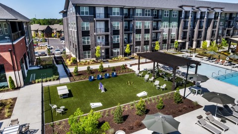 A large outdoor swimming pool area with a grassy area and a pavilion.