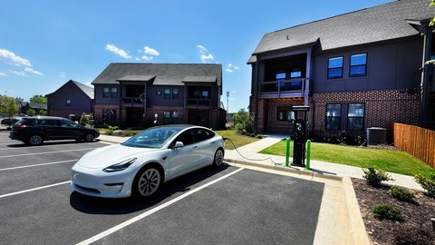 A white Tesla car is parked in a parking lot.