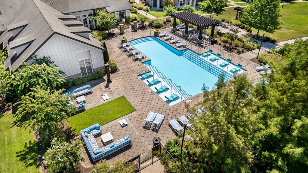 A large outdoor swimming pool surrounded by lounge chairs and umbrellas.
