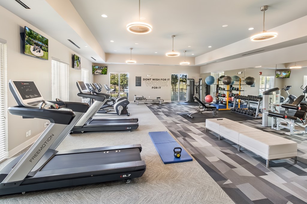 A gym with treadmills, weights, and exercise equipment.