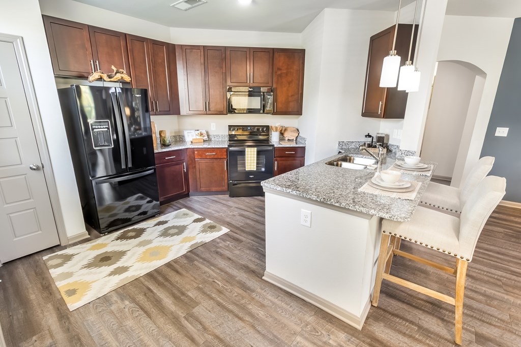 A kitchen with a black fridge and wooden cabinets.