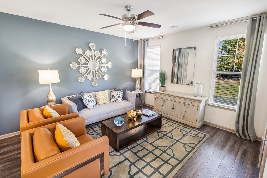 A living room with a brown sofa, a coffee table, and a ceiling fan.