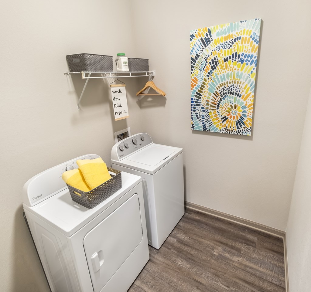 A laundry room with a washer and dryer and a shelf with a sign that says "wash, dry, fold, repeat.".