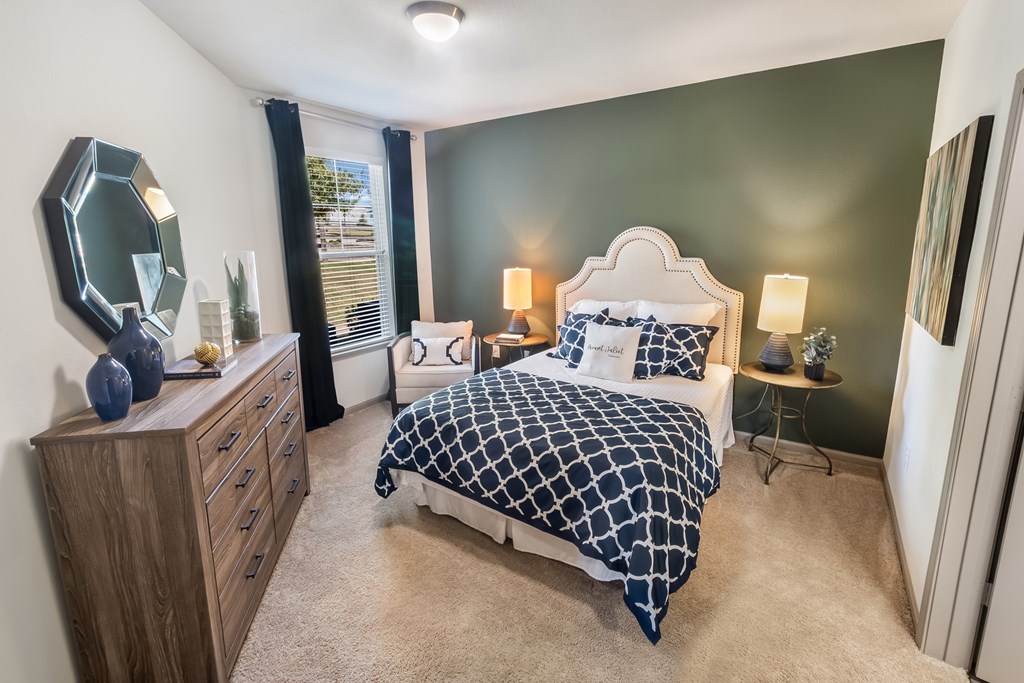 A bedroom with a bed, nightstand, and a mirror on the wall.