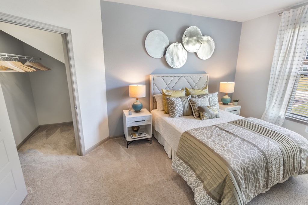 A bedroom with a large bed and a small nightstand with a lamp.