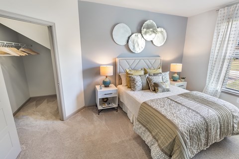 A bedroom with a large bed and a small nightstand with a lamp.