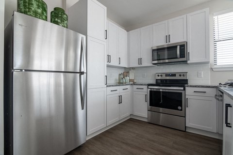 a white kitchen with stainless steel appliances and white cabinets
