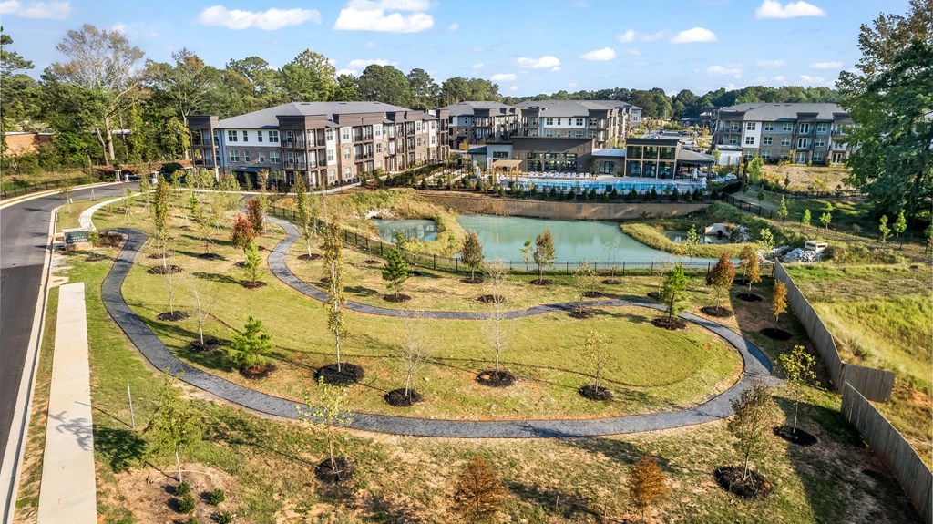 an aerial view of a park with a pond and buildings