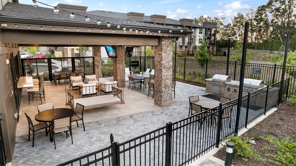 a patio with tables and chairs and a grill