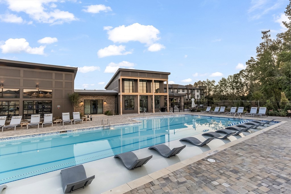 a swimming pool with chairs and a building in the background