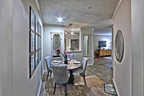 A dining room with a table set for two and a mirror on the wall.