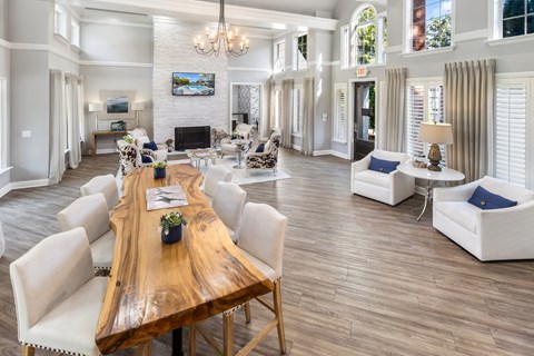 A large, well-lit living room with a wooden dining table and white chairs.