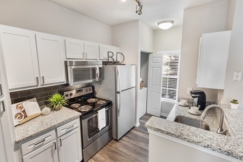 A kitchen with white cabinets and a granite countertop.