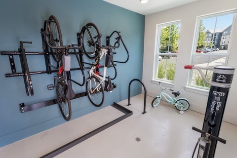 A room with a blue wall and a white floor has a bike rack with several bicycles hanging on it.
