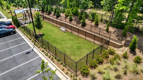 A parking lot with a fence and trees in the background.