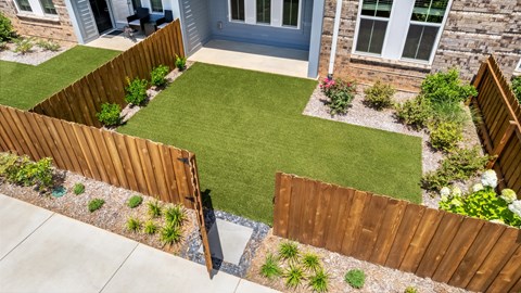 A backyard with a wooden fence and a green lawn.