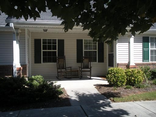 A house with a white porch and a green bush.