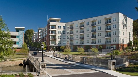 A modern apartment building with a bridge over a small pond.