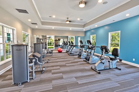 A gym with a variety of equipment including treadmills, weights, and exercise machines.