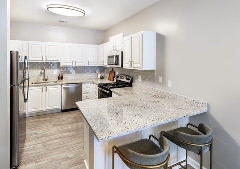 a kitchen with white cabinets and a marble counter top
