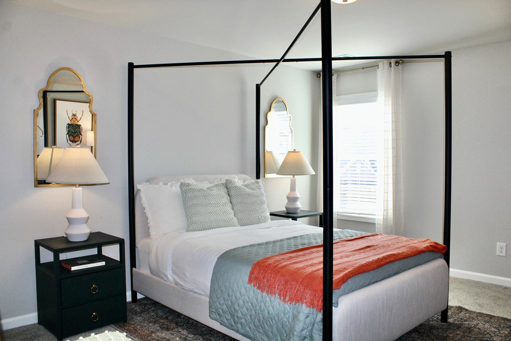 a bedroom with a white bed and a black canopy bed