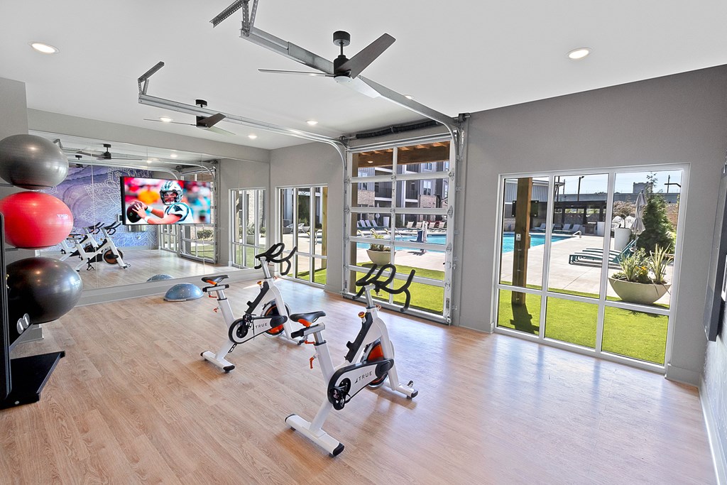 a gym with a view of a swimming pool and a workout area with exercise equipment