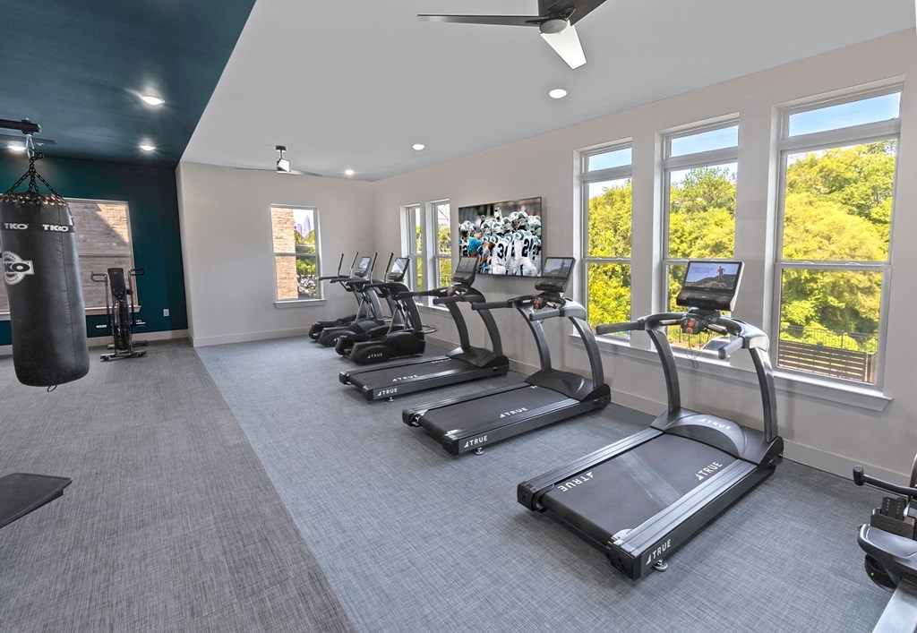 a gym with cardio equipment and windows in a building
