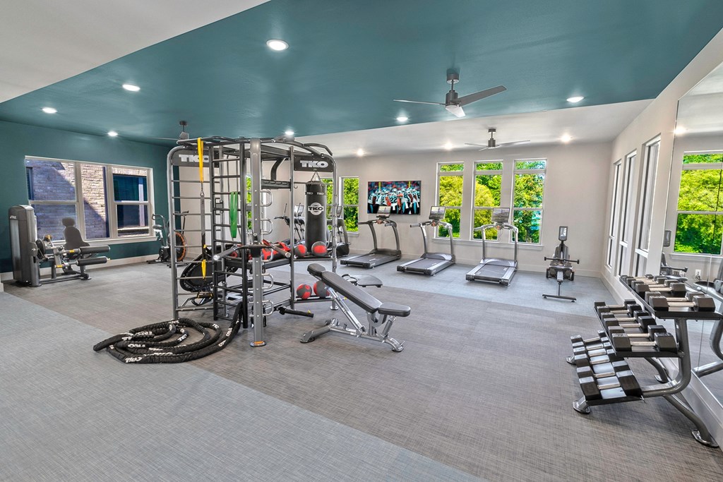 a home gym with weights and cardio equipment and windows