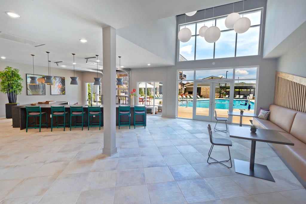 the lobby of a clubhouse with tables and chairs and a swimming pool