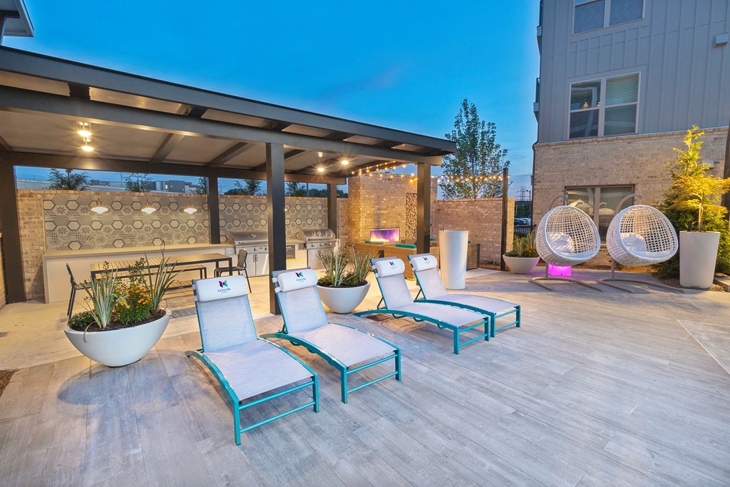 a patio with blue lounge chairs and a fire pit