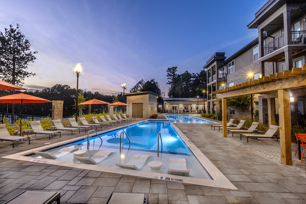 a swimming pool with chairs and umbrellas at night