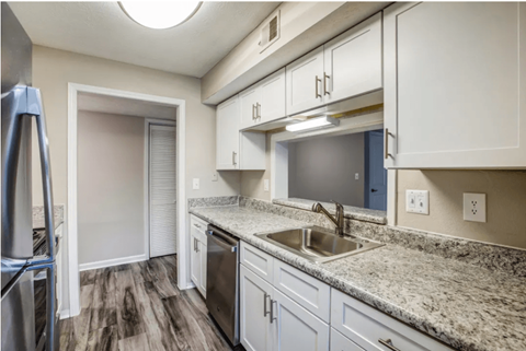 a kitchen with white cabinets and granite counter tops and a sink