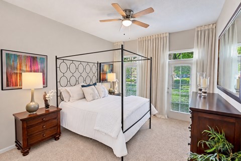 A bedroom with a four poster bed and a ceiling fan.
