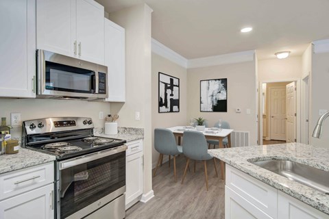 A kitchen with a stove, microwave, and a dining table with chairs.