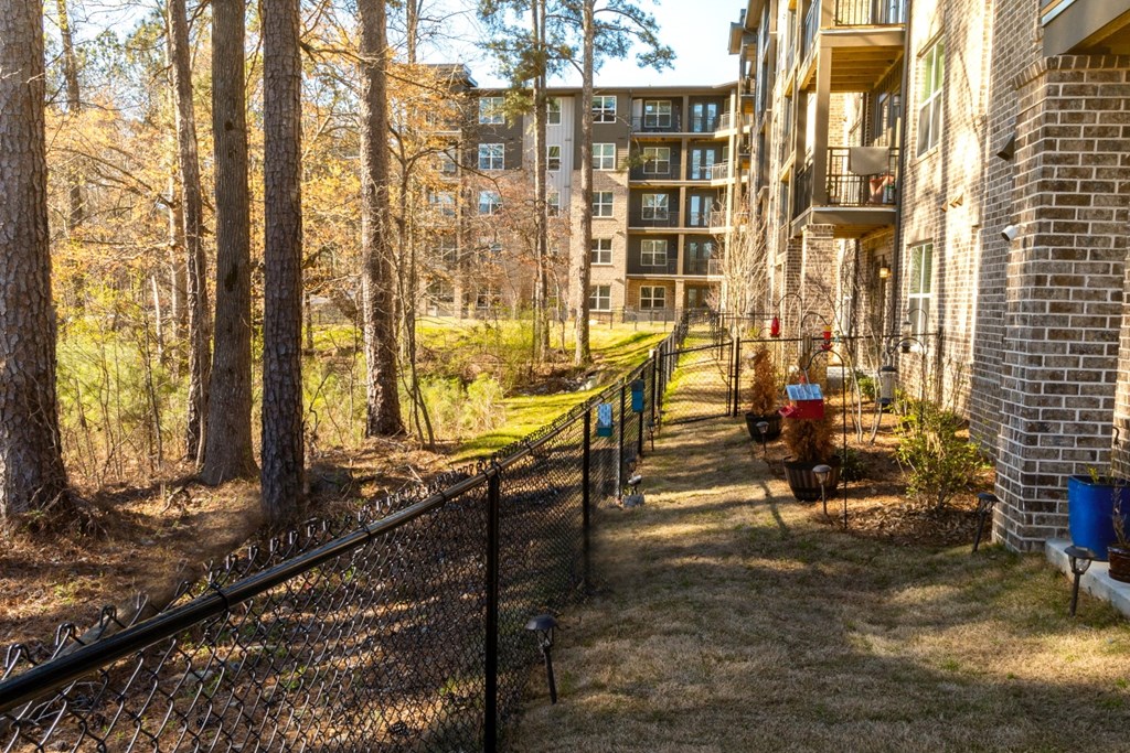 a fenced in yard with trees and an apartment building