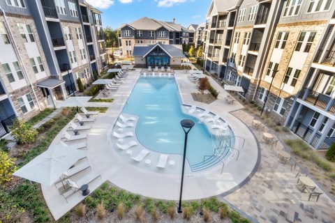 A large outdoor swimming pool surrounded by lounge chairs and umbrellas.