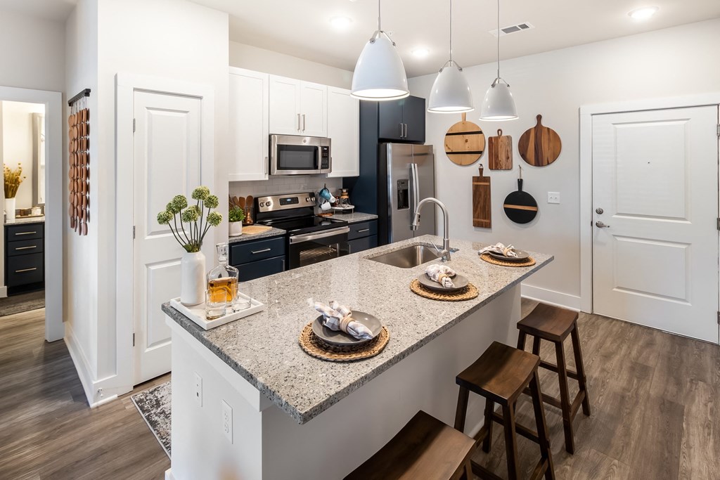 an open kitchen with a marble counter top and a sink