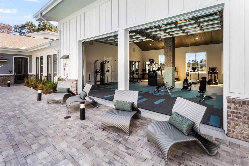 a patio with chairs and a gym in the background