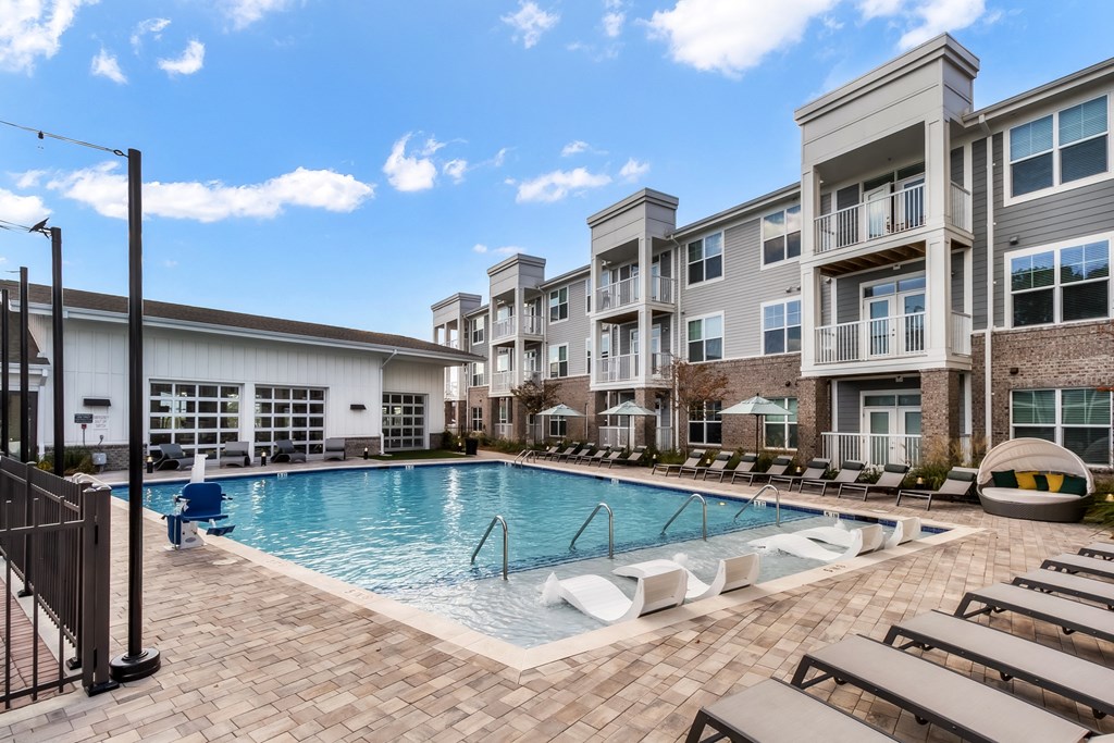 a swimming pool with lounge chairs in front of an apartment building