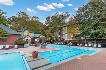 A large swimming pool surrounded by lounge chairs and trees.