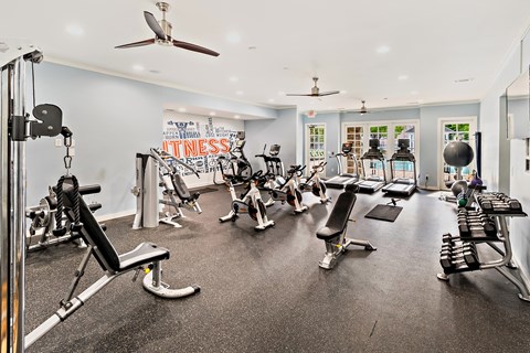 A gym with a variety of equipment including treadmills, weights, and exercise machines.