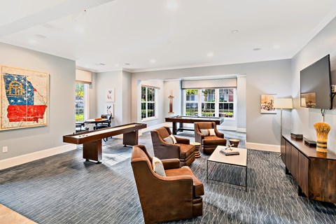A living room with a grey carpet and brown leather chairs.