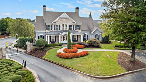 A large house with a grey roof and a white fence.