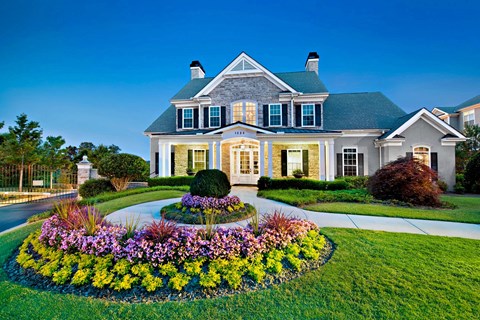 A large house with a well-manicured lawn and a flower bed in front.