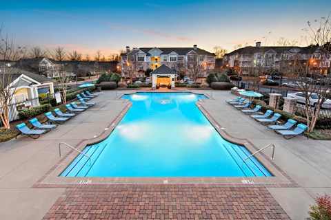 A large swimming pool surrounded by lounge chairs and umbrellas.
