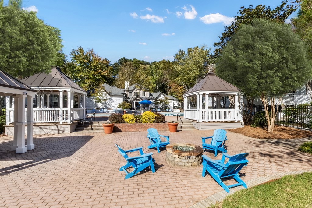 A gazebo surrounded by blue chairs and a brick walkway.