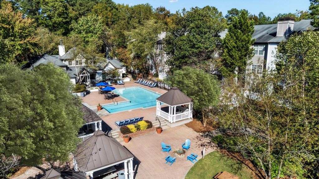 A pool surrounded by trees and a gazebo.