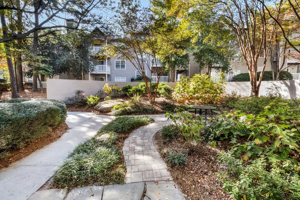 A pathway leads through a landscaped area with a building in the background.