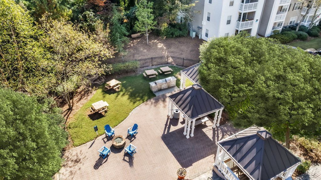 A bird's eye view of a backyard with a gazebo, lawn chairs, and a fire pit.